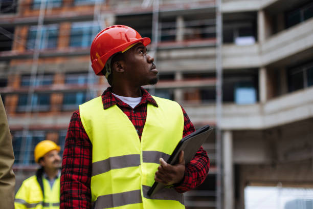 Young construction worker looking up at the building site